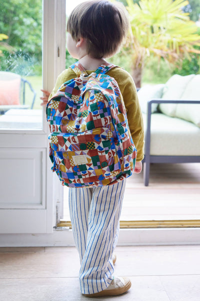 Child wearing a colourful backpack indoors