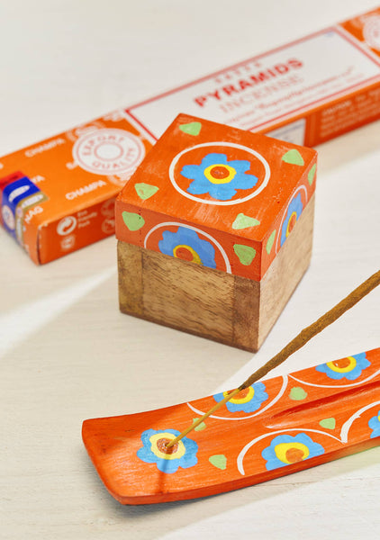 Decorative wooden box and incense catcher with colourful designs on a light background