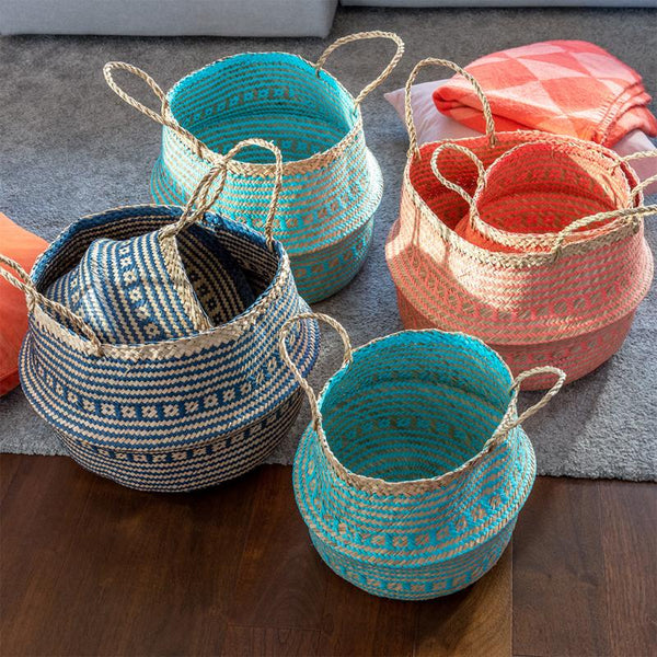 Set of colourful woven baskets on a wooden surface with a grey rug in the background.