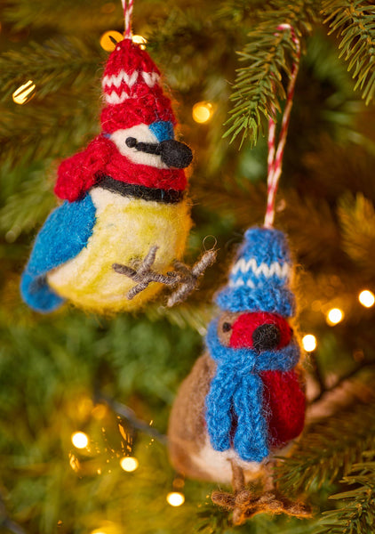 Two knitted bird ornaments on a Christmas tree with lights in the background
