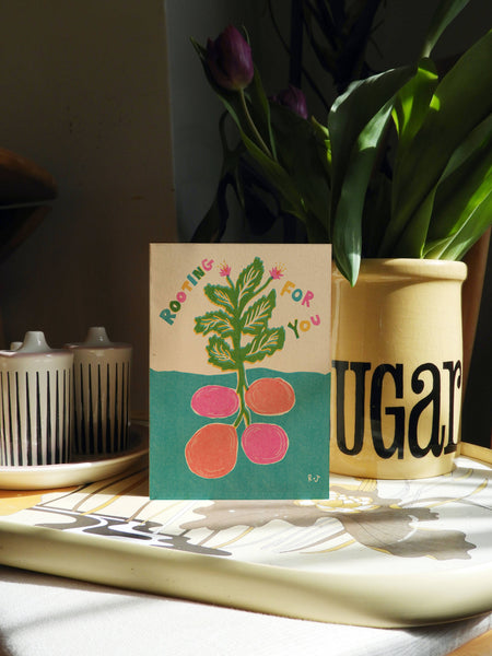 Card with plant design on a table with a vase and tulips in the background
