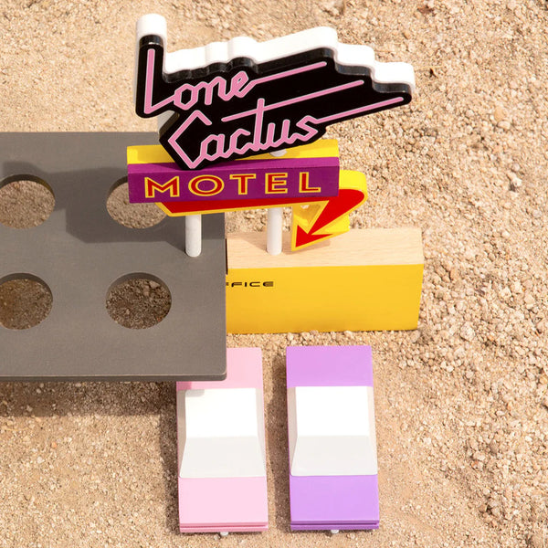 Model of a neon sign for 'Lone Cactus Motel' on a sandy surface.