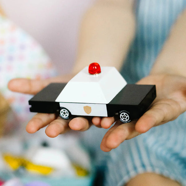 Small model of a police car held in hands with a blurred background