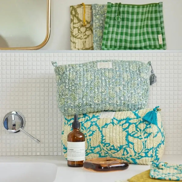 Patterned pouches on a bathroom counter with a bottle and soap dish.