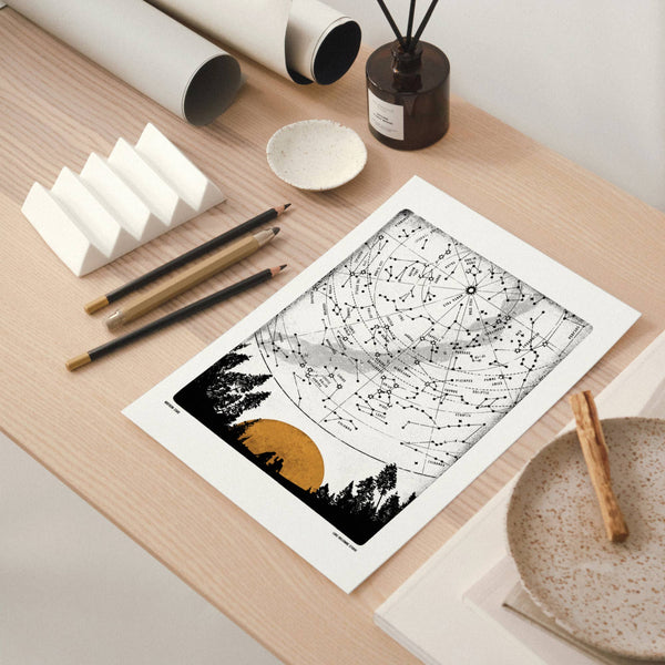 Black and white art print on a wooden table with stationery items.