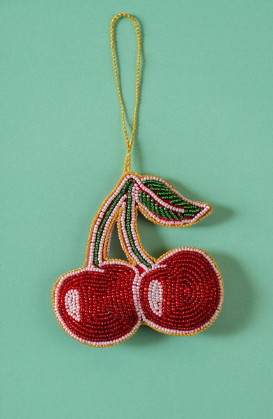 Beaded cherry ornament on a green background