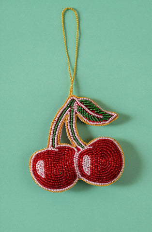Beaded cherry ornament on a green background