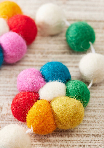 Colourful felt ball garland on a textured surface