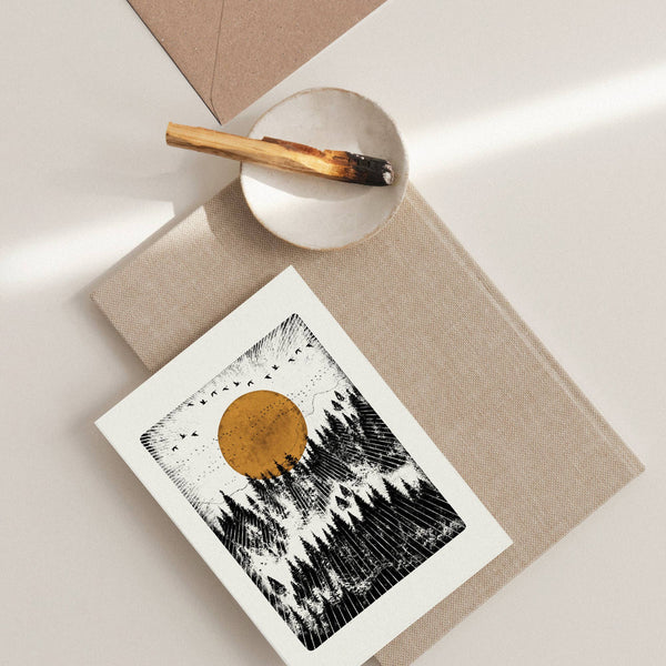 Greeting card with a sun and mountain design on a textured surface