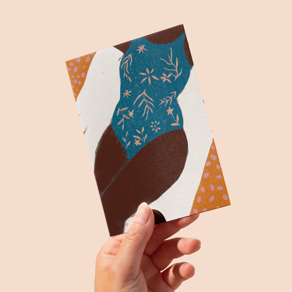 Hand holding a decorative card with abstract design on a beige background