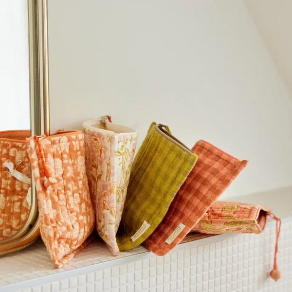 Set of colourful fabric pouches on a white surface with a neutral background
