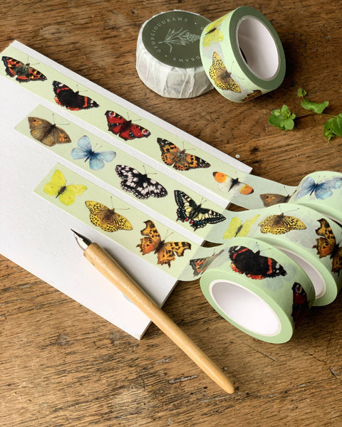 Butterfly-themed tape rolls on a wooden surface with a pen.