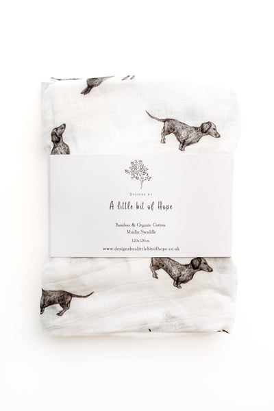 Baby blanket with dachshund pattern and brand label on a white background