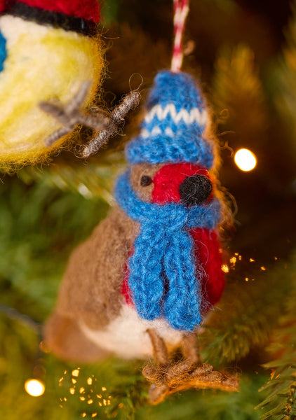 Small knitted robin decoration wearing a blue hat and scarf on a Christmas tree.