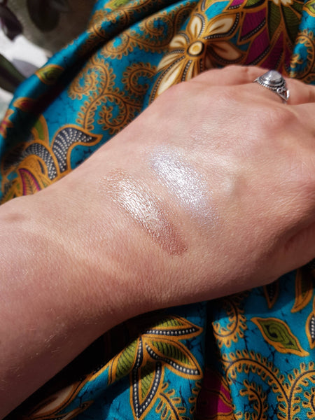 Hand with glittery substance on skin against a colourful patterned fabric background