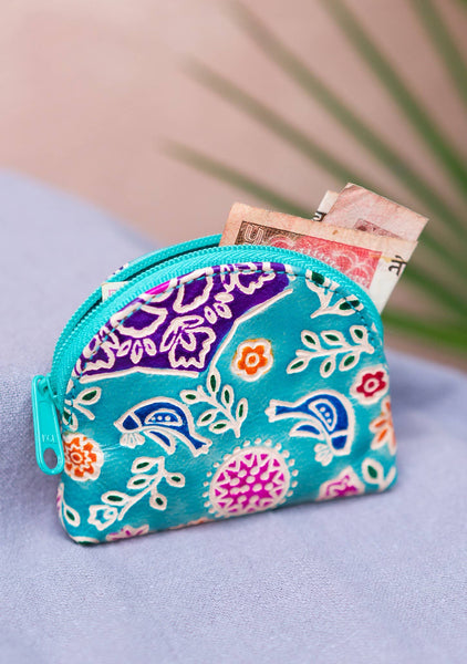 Colourful floral-patterned coin purse with money on a light purple surface