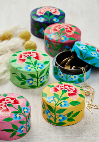 Colourful floral-patterned jewellery boxes on a light wooden surface.