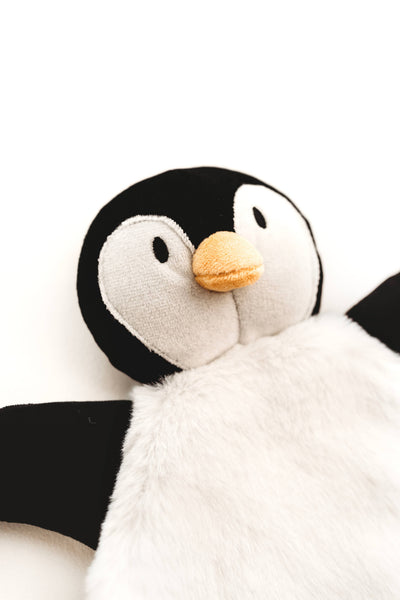 A close-up of a plush penguin toy with a black and white body, a soft orange beak, and embroidered eyes, photographed against a plain white background.