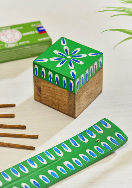 Green and brown wooden box and incense holder with decorative patterns on a light surface.
