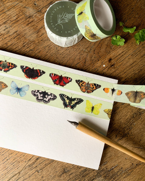 Butterfly-themed washi tape on a wooden surface with a pencil.