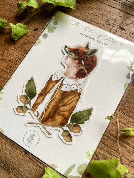 Sticker of a girl wearing a fox mask with leaves on a wooden surface