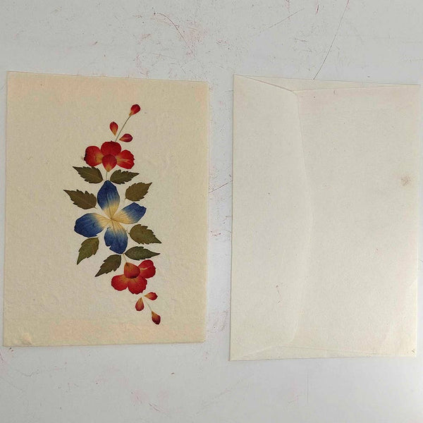 Floral design on a beige card with a plain white envelope beside it.
