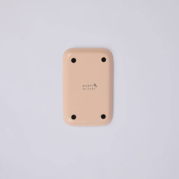The back of a pink, rectangular iron tray with rounded corners, four black protective feet, and the 'paper mirchi' logo printed in the centre, shown on a light grey background.