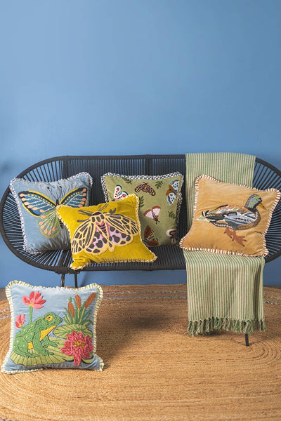 Decorative pillows with animal designs on a wicker chair against a blue wall.