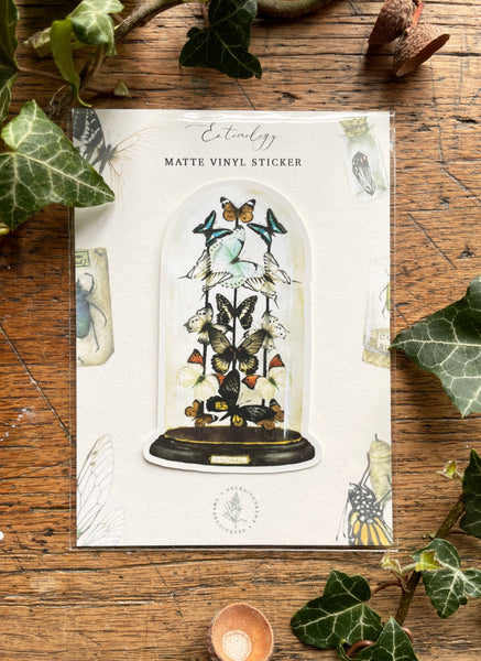 Matte vinyl sticker packaging with butterfly design on a wooden surface with ivy leaves.
