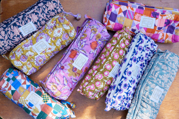 Colorful fabric pencil cases with floral and patchwork patterns on a wooden surface