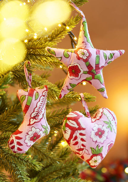 Decorative Christmas ornaments shaped like a star, heart, and stocking hanging on a tree.