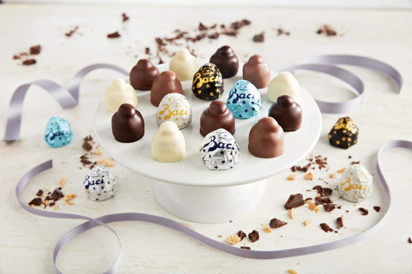 Assorted chocolates on a white plate with decorative ribbons on a light background