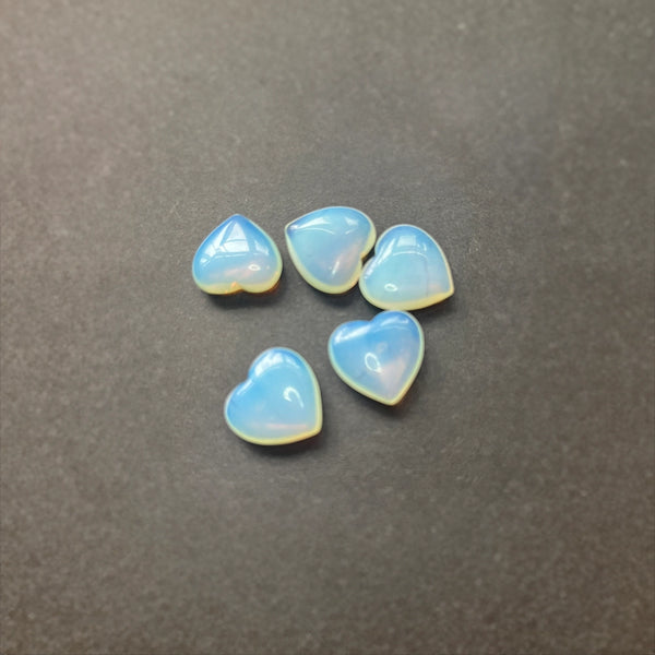 Five heart-shaped opalite crystals on a dark grey background