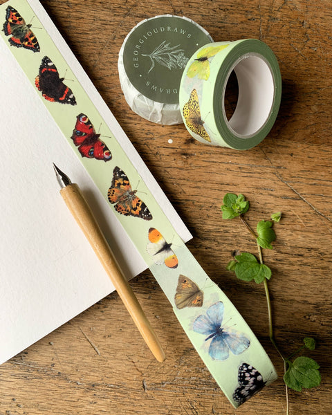 Butterfly-themed tape with a pen and paper on a wooden surface