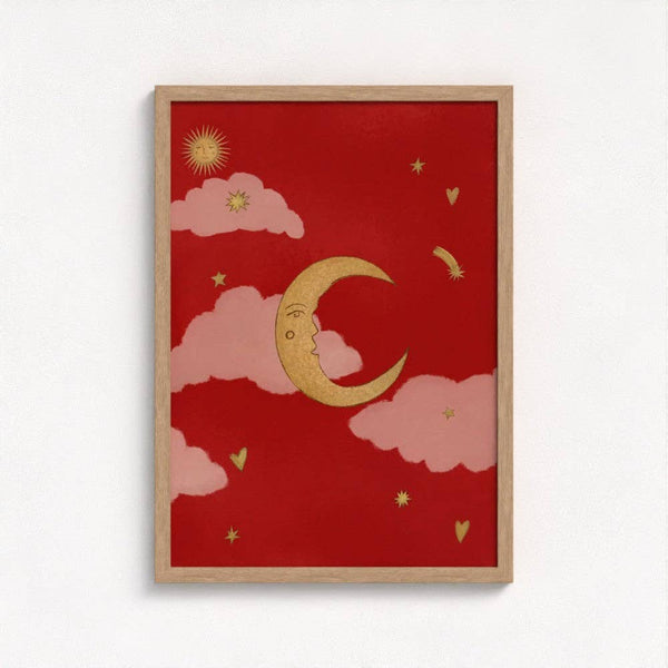 Framed artwork with a red background, gold crescent moon, pink clouds, and yellow stars on a white wall.