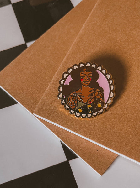 Pin with a stylised illustration of a woman on a brown card against a checkered background