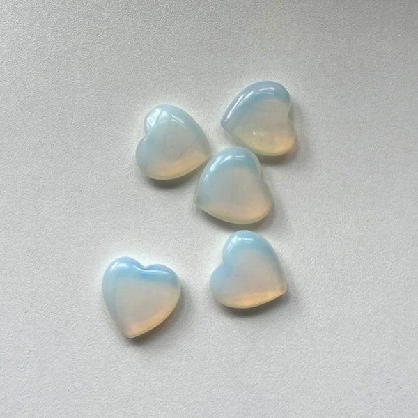 Five heart-shaped opal gemstones on a light grey background
