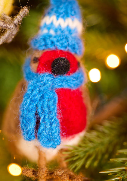 Knitted gnome ornament with blue hat and red face on a Christmas tree.