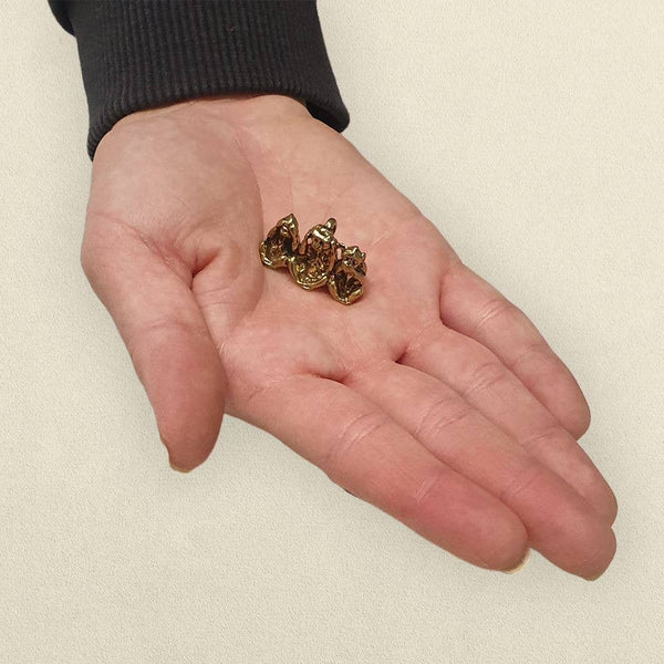 Small gold figurine held in a hand against a beige background