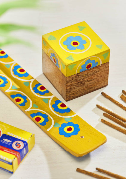 Wooden box and incense catcher with colourful floral patterns on a light background