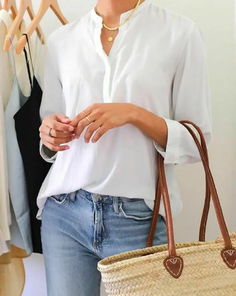 Person wearing a white shirt and blue jeans with a straw bag, standing in front of a rack.