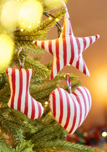 Red and white striped heart and star Christmas ornaments on a tree with a blurred festive background.