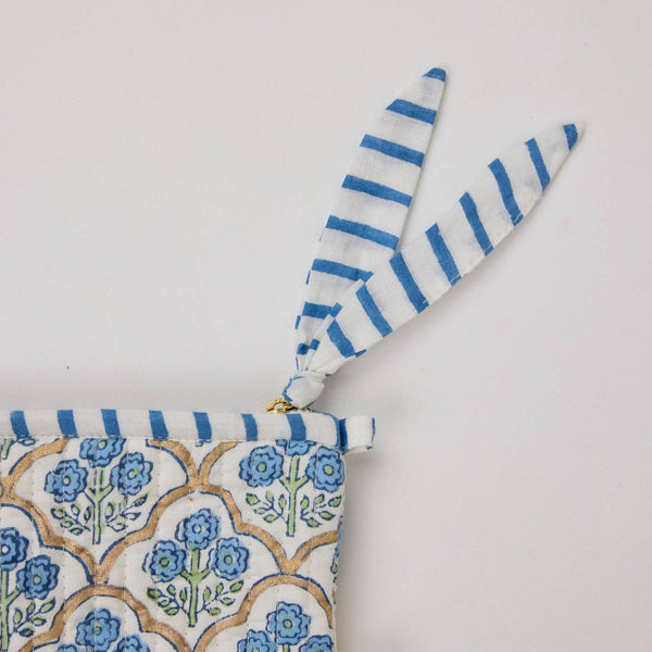 Blue and white floral-pattern cosmetic bag with a striped trim on a light background