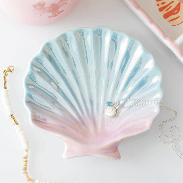 Shell-shaped dish with a necklace on a light background