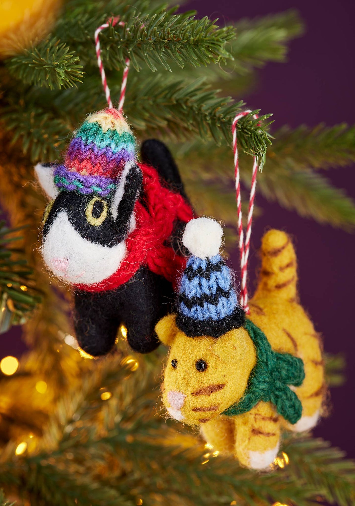 Knitted cat ornaments on a Christmas tree with colourful hats and scarves.