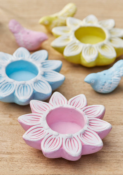 Colourful ceramic flower-shaped candle holders on a wooden surface