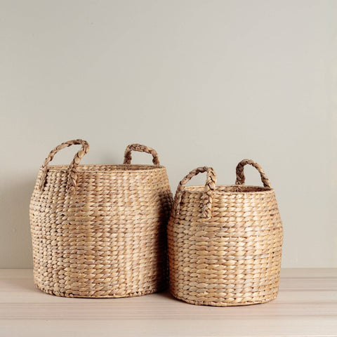 Two woven baskets with handles on a neutral background