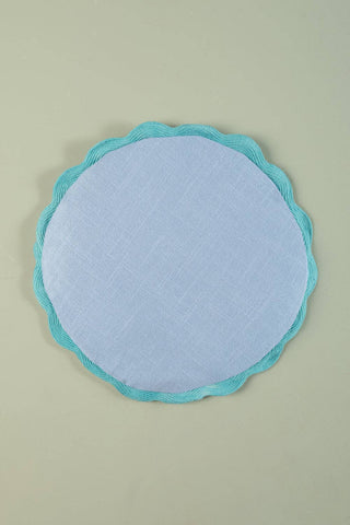 Round light blue cushion with turquoise rim on a beige background