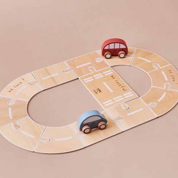 Wooden toy race track with two cars on a beige background