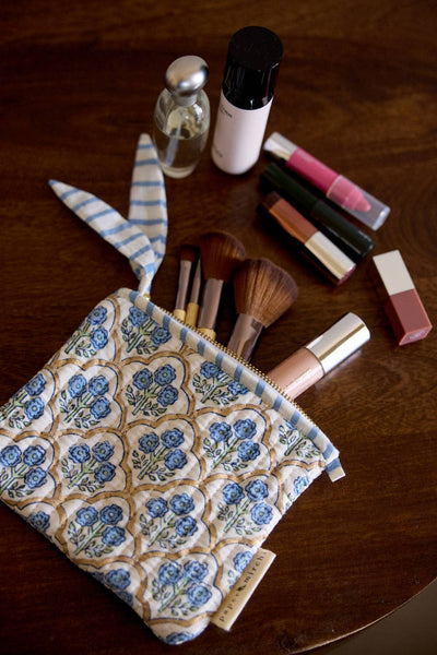 Makeup bag with floral pattern containing makeup items on a wooden surface